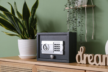 Modern safe with plant and decor on commode in room