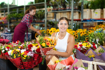 Young woman choosing bouquet of flowers in flower shop