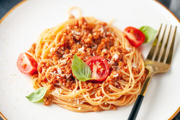 Pasta Spaghetti Bolognese in white plate on gray background. Bolognese sauce is classic italian cuisine dish. Popular italian food.