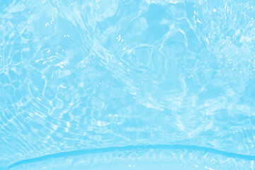 Blue water with ripples on the surface. Defocus blurred transparent blue colored clear calm water surface texture with splashes and bubbles. Water waves with shining pattern texture background.
