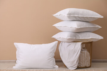 White pillows, storage basket and blanket near beige wall