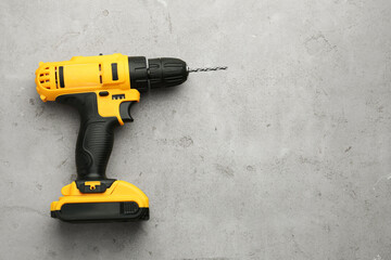 Modern cordless electric drill on light grey table, top view. Space for text
