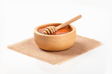 Wooden bowl with organic honey and honey dipper isolated on white background.