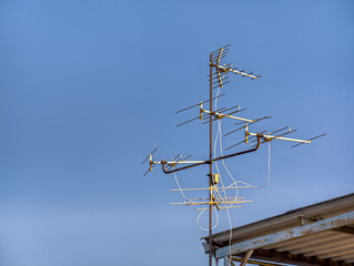 An old technology TV antenna in the evening sky on the roof.