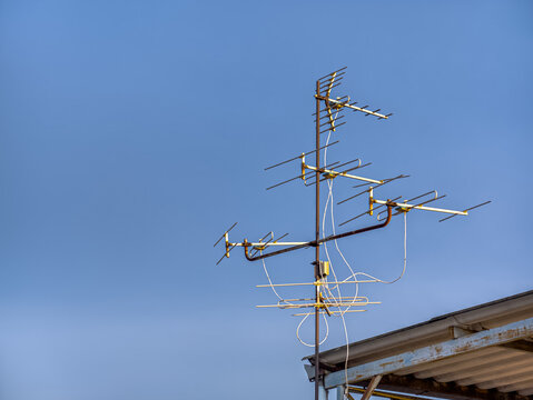 An old technology TV antenna in the evening sky on the roof.