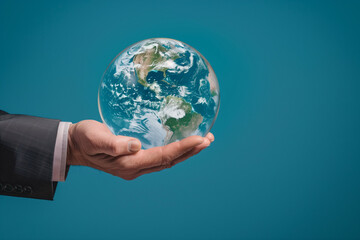 Conceptual Image of a Businessman Holding a Transparent Globe Showing North America in a Studio with a Blue Background