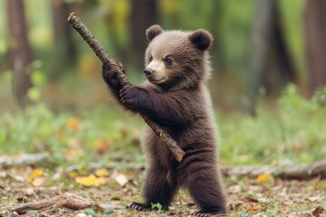 Obraz premium A playful bear cub holding a stick, surrounded by lush greenery in a vibrant forest setting, showcasing wildlife's innocence.