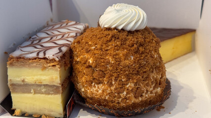Close-up of assorted pastries, including a Mille-feuille and a crumb-coated cream-filled dessert, topped with decorative frosting