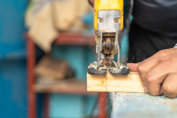 Woodcarver using jigsaw to cut wood in workshop