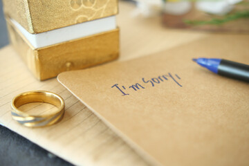 Note with the sorry word next to a wedding ring.