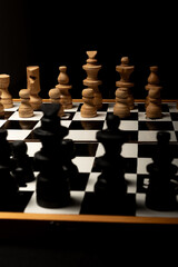 An intense chess match captured in dim light, highlighting wooden pieces as they face off in a...