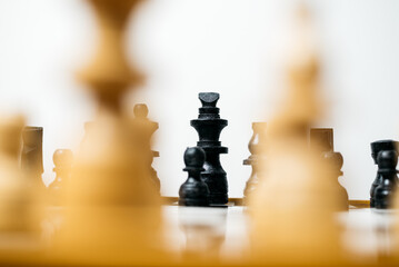 Close-up of a chessboard, focusing on the black king surrounded by blurred wooden pieces, symbolizing the intense strategic battle unfolding © Martanto Setyo H