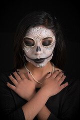 Woman with day of the dead makeup hugging herself
