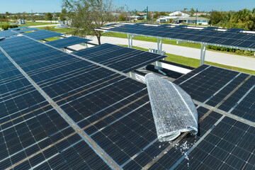 Hurricane wind damage to solar panels installed as shade roof over parking lot for parked electric...