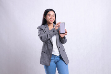 Naklejka premium charm beautiful young office woman smile to camera both hands holding sideways showing cellphone screen wearing gray suit isolated on white background. for technology, lifestyle, promotion content