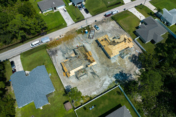 Professional builders working on roof construction of unfinished suburban home with wooden frame structure in Florida rural area. Concept of housing development in America