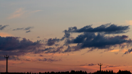Power line in a field against the backdrop of the evening sunlight. High voltage electric transmission tower.
