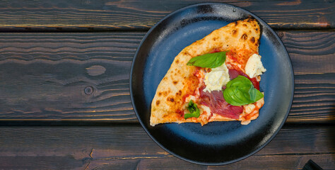 Top view of Italian pizza with one slice on wooden table. Italian Pizza Manzo. Space for text.