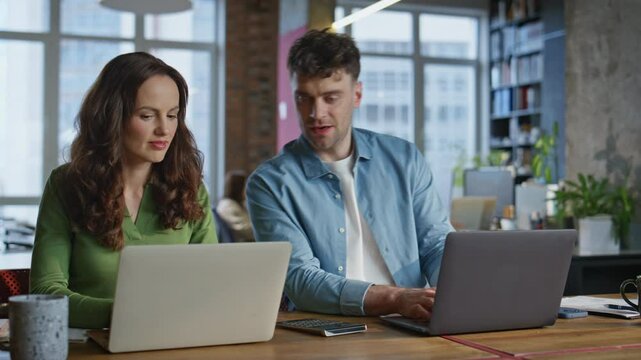 Smiling interns work laptops sitting modern coworking space together closeup. 