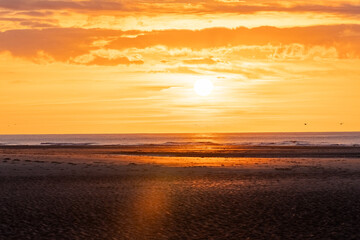 Obraz premium The golden sun sets over a tranquil beach, creating a serene horizon and captivating with peaceful beauty