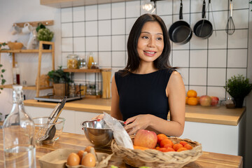 A beautiful, positive Asian woman is cooking a healthy recipe in the kitchen.