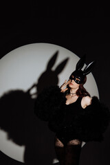 A woman in a black outfit with a rabbit mask on her face. The image has a dark and mysterious mood