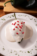 Chiles en Nogada, Typical dish from Mexico. Prepared with poblano chili stuffed with meat and fruits and covered with a walnut sauce, parsley and pomegranate.