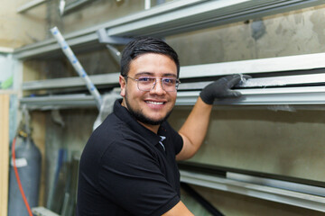 A man in a black shirt is smiling and holding a piece of metal. Concept of happiness and accomplishment, as the man is proud of his work