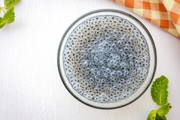 Hairy basil seed in a glass cup  on white background, top view food table