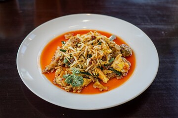 A plate of Hawker-style Oyster Omelette containing stir-fried oyster and fried egg, bean sprouts,...