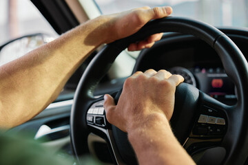Close up of hands gripping a car steering wheel in a modern vehicle interior Soft focus on dashboard elements adds depth