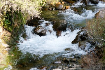 Fototapeta premium Water flows over the rusty brown rocks at The Silica Rapids