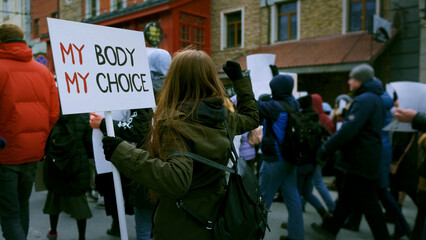 Feminist demonstration city street. Legal abortion protest. Girl hold feminism placard. banner. Roe v wade law. Angry women crowd. Lot female people fight rights. Many activists walk. My body picket.