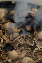 Cooking walnut ash in a cast iron pot. Open fire.