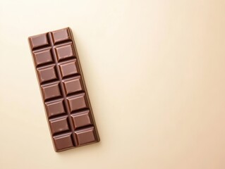 Obraz premium A delicious chocolate bar displayed on a soft beige background, perfect for showcasing indulgence and sweetness.