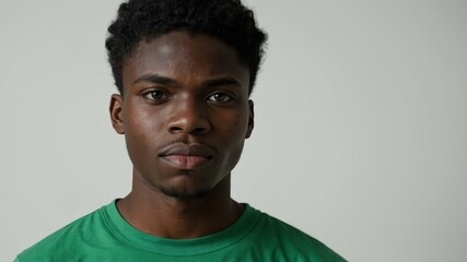 Obraz premium teen stunning black hair subsaharan african man with generic shirt model portrait standing straight on a white wall for ad concept space for text