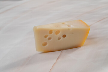 A large piece of cheese with holes on a light white table