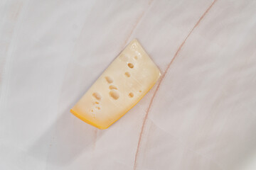 A large piece of cheese with holes on a light white table