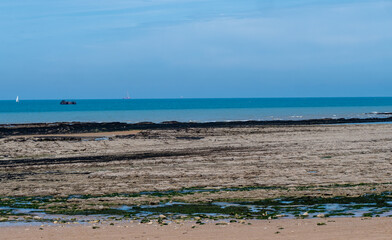 A beach with a boat in the distance and a blue sky