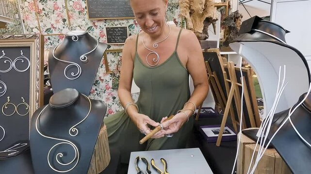 4k Video at 25 fps of a Smiling Hispanic Woman Around 50 Years Old Crafting an Aluminum Wire Ring at Her Street Stall at Night for Sale