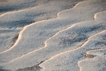 Close up of a sandy beach with waves gently rolling in
