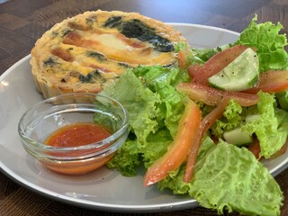 A plate of smoked beef and cheese quiche, salad and chili sauce