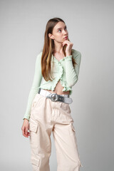 Young Woman With Long Brown Hair Posing Thoughtfully Against White Background