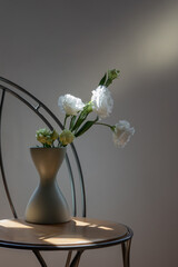 beautiful flowers in vase on vintage table in sunlight