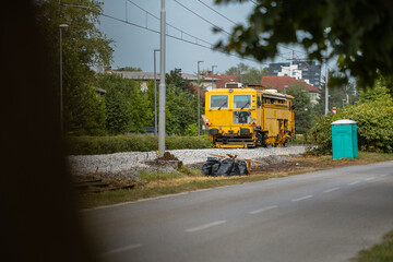 Heavy machinery on a railway tack that is under renovation. Fresh track laid and machines used to level the rails and align the gravel track bed. Ballast tamper in action