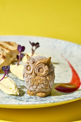 artistic presentation of pate shaped into adorable owls. Served on a plate with toasted bread and garnished with fresh herbs