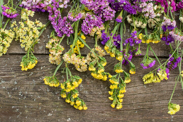Multicolored kermek and statice flowers on rough wooden background. flat lay top view. floral background on rough boards.