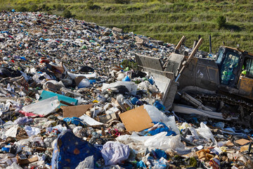 Heavy machinery shredding garbage in an open air landfill. Pollution