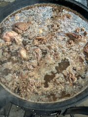 The meat is cooked in a cauldron over a fire