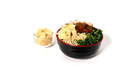 A bowl of Mie Ayam, a typical Indonesian dish, featuring chicken noodles with shredded chicken, meatballs, dumplings, green vegetables, and a variety of toppings, isolated on a white background